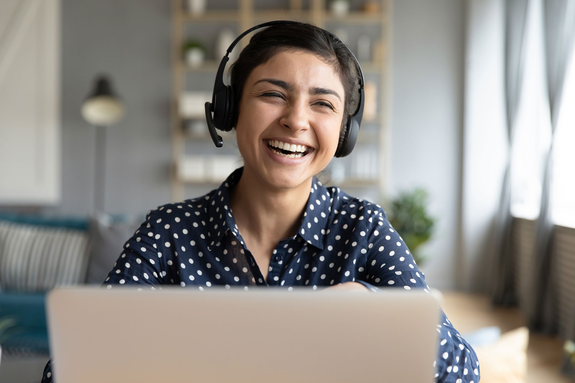 Laughing woman wearing headset working on laptop